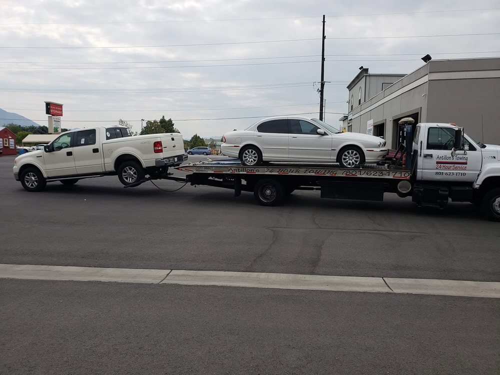Antillon's flatbed loaded with a sedan and towing a pickup behind it