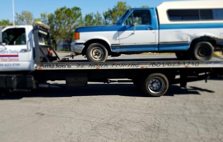 Blue and white Ford pickup loaded on an Antillon's flatbed